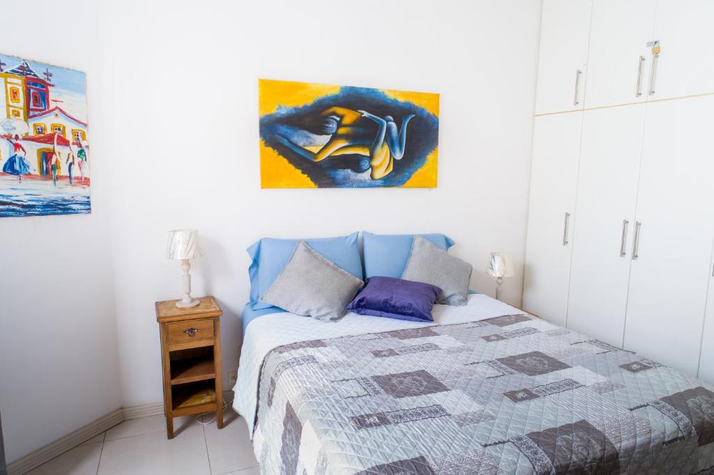 1 dormitorio con 1 cama y una pintura en la pared en Lindo apartamento de 2 quartos ao lado da Praia de Copacabana!, en Río de Janeiro