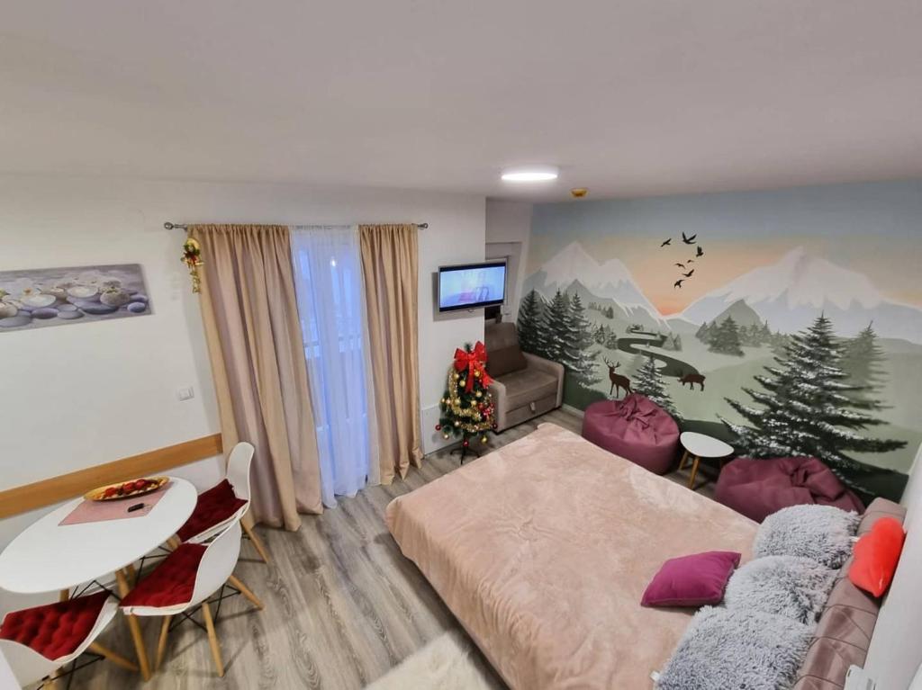 a living room with a bed and a table and a tv at Snowman Studio Apartment Jahorina in Jahorina