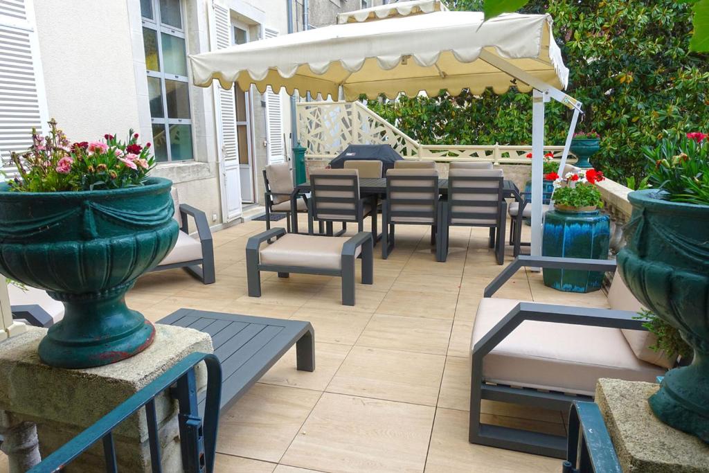 a patio with chairs and tables and an umbrella at EXCEPTIONNEL PROPRIETE STANDING 90 m2 PARKING PRIVE BEL EXTERIEUR CENTRE VILLE CLIMATISE in Périgueux