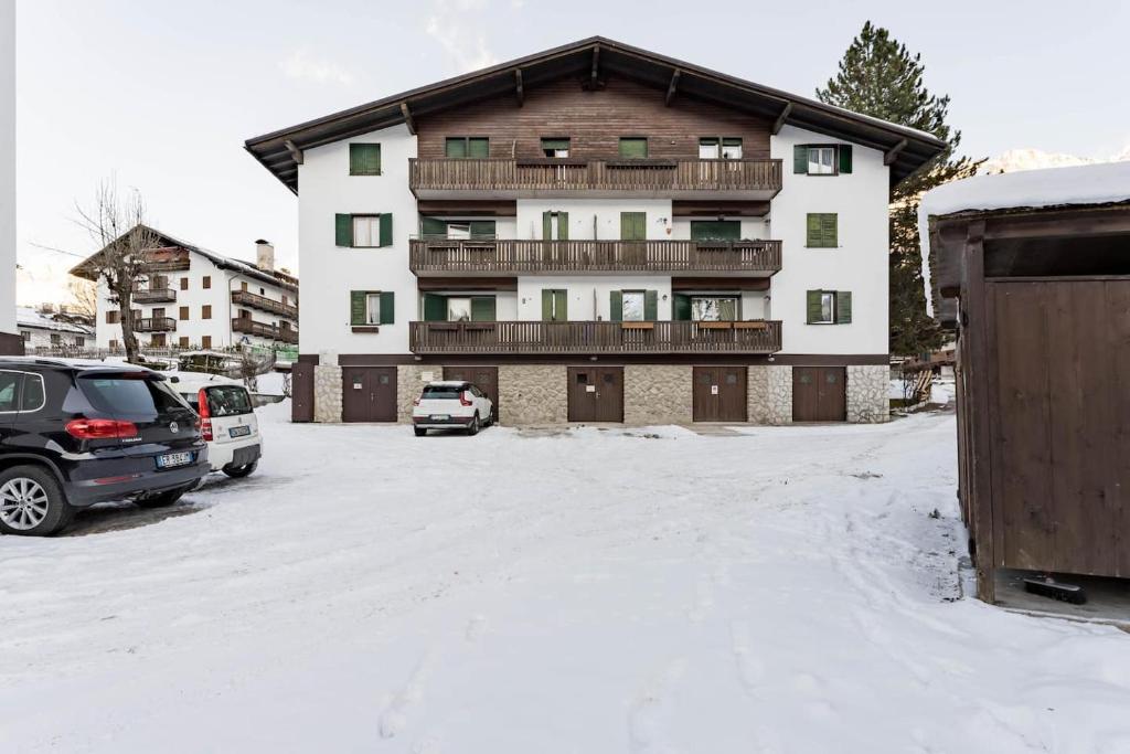 un aparcamiento cubierto de nieve frente a un edificio en Cortina Comfort House en Cojana