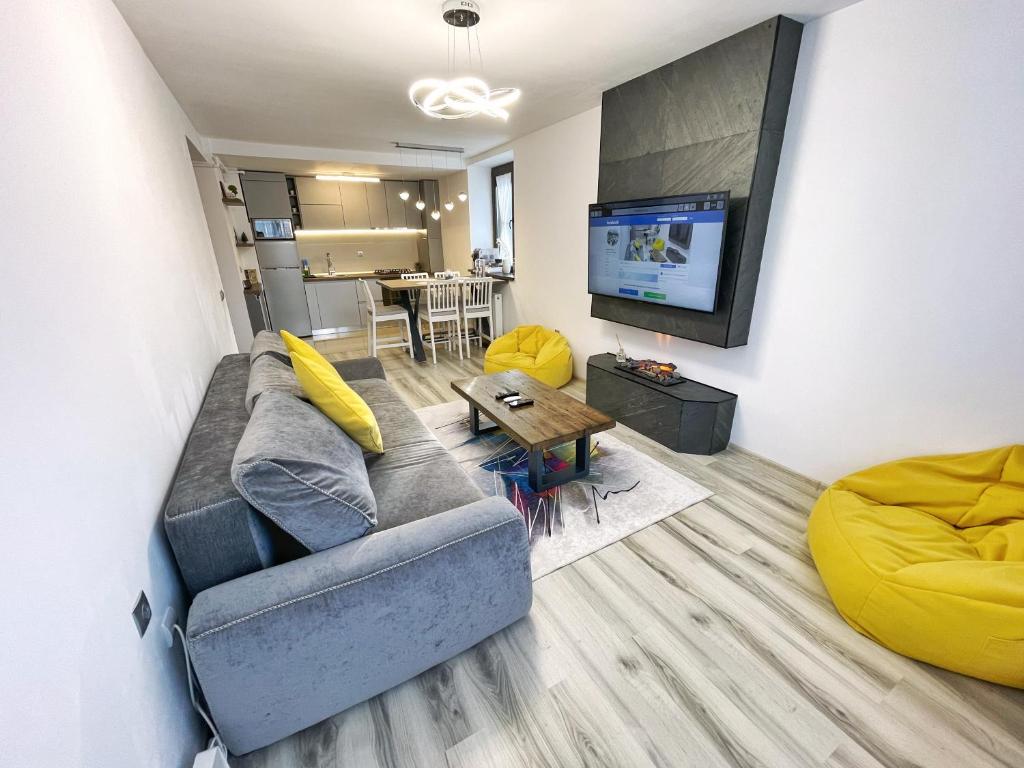 uma sala de estar com um sofá, uma mesa e uma televisão em Perfect View Apartment em Sinaia