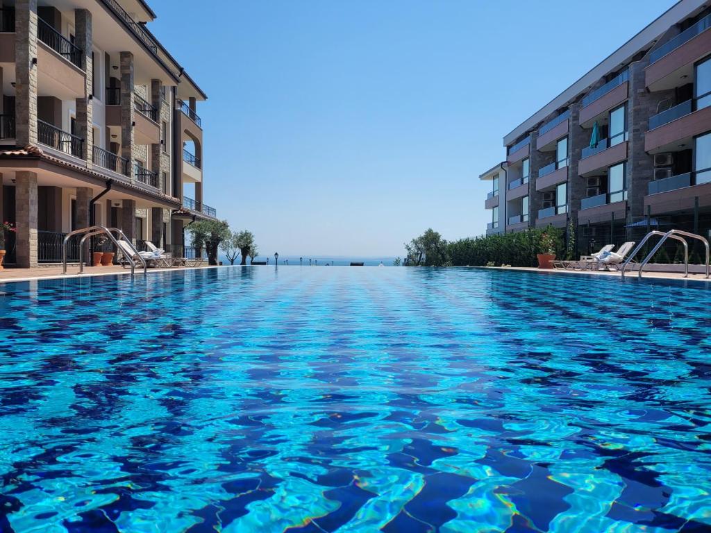 a swimming pool with blue water between two buildings at Bayview B32 - Burgas Beach Resort in Burgas City