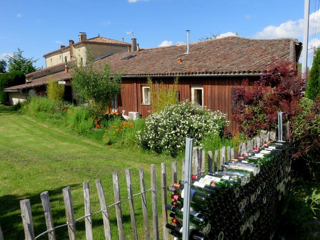 une maison avec une clôture et des bouteilles de vin dans l'établissement Le Chai de Mario, à Sadirac