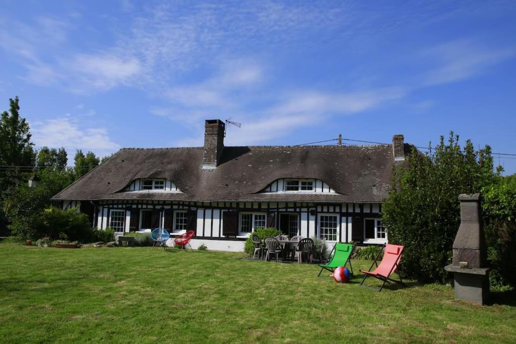 a large house with two lawn chairs in front of it at Belle Longère normande, cheminée et jardin arboré in Canville-les-Deux-Églises