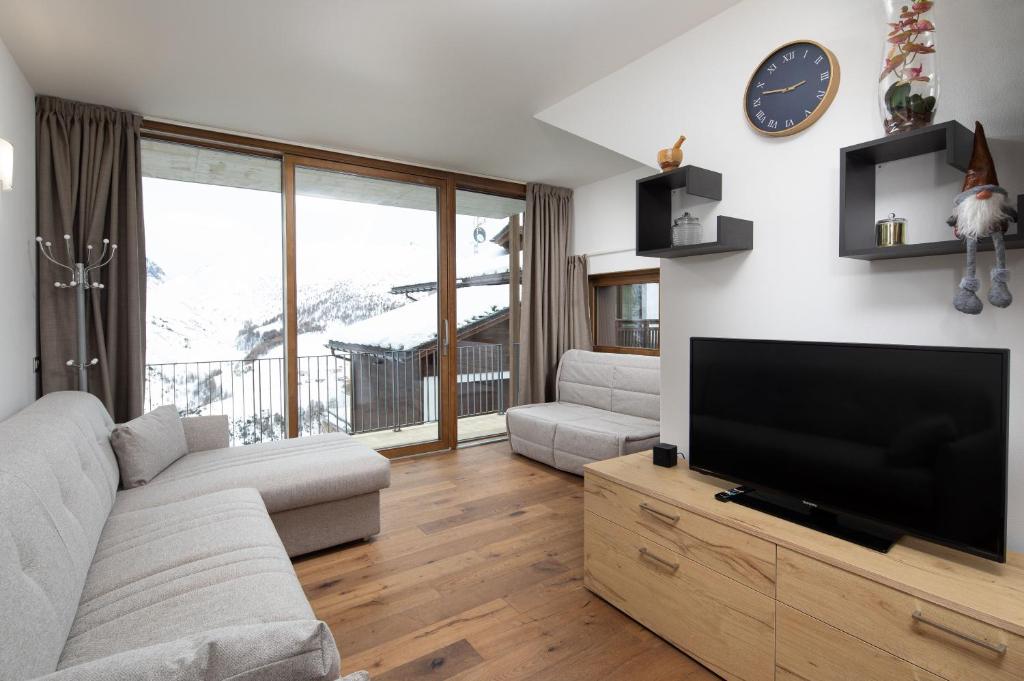 Casa Noemi في ليفينو: غرفة معيشة مع تلفزيون بشاشة مسطحة وأريكة
