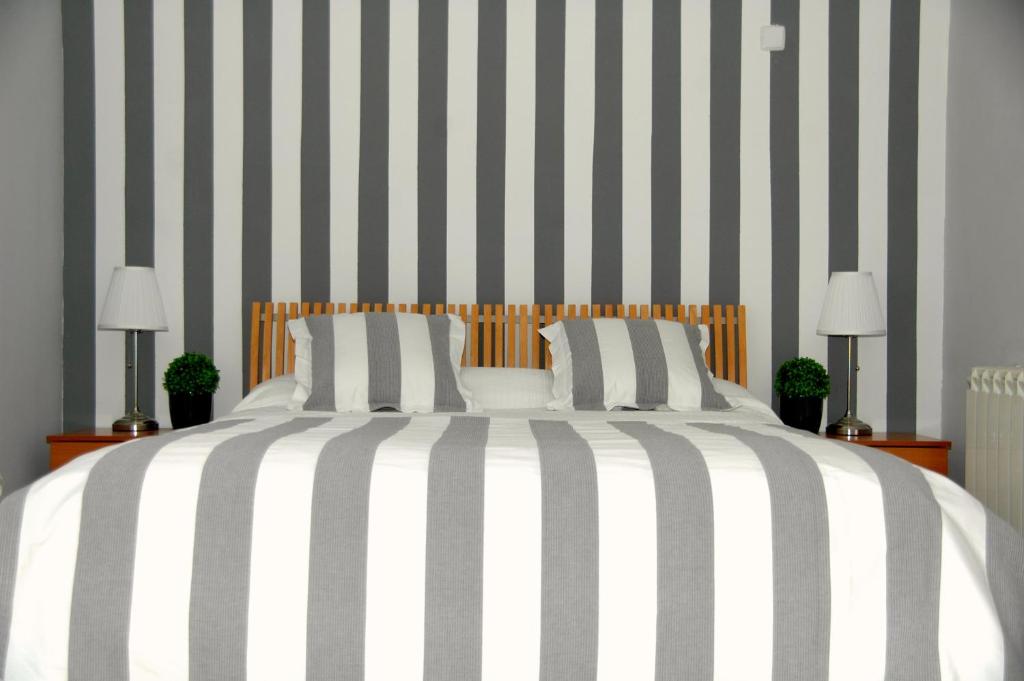 a bedroom with a large bed with black and white stripes at Hostal Cervantes in Daganzo de Arriba