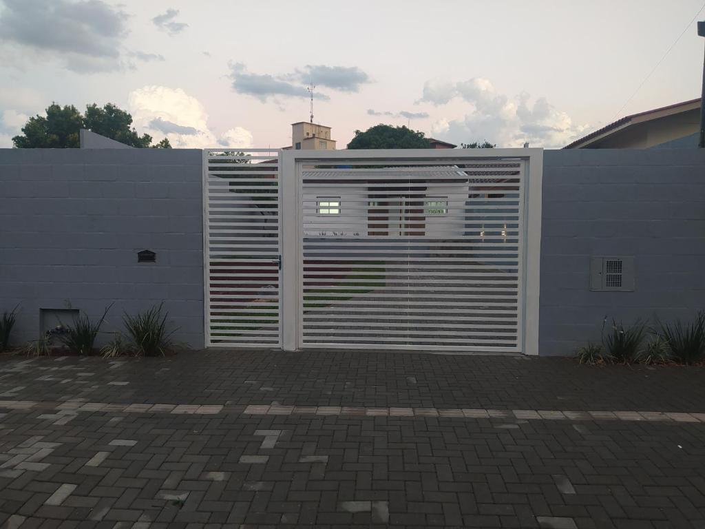 a white fence with a gate in front of a building at Trentino 66 - Hospedagem em Ijuí, casa agradável com estacionamento in Ijuí