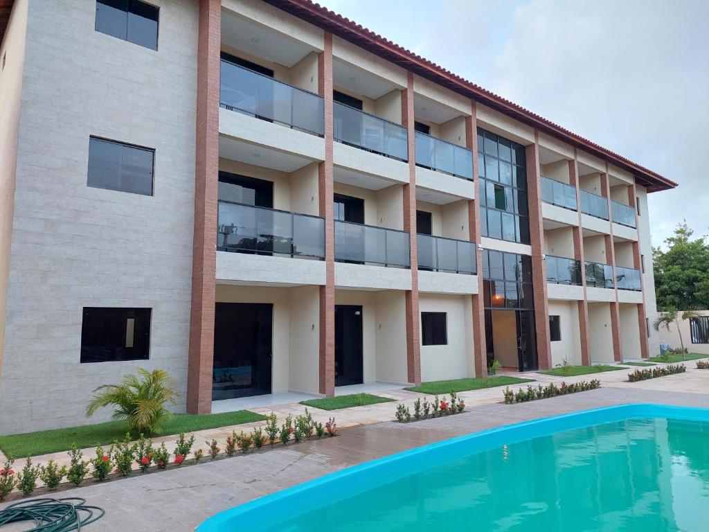 an apartment building with a swimming pool in front of it at Flat Casa da Praia in Porto De Galinhas