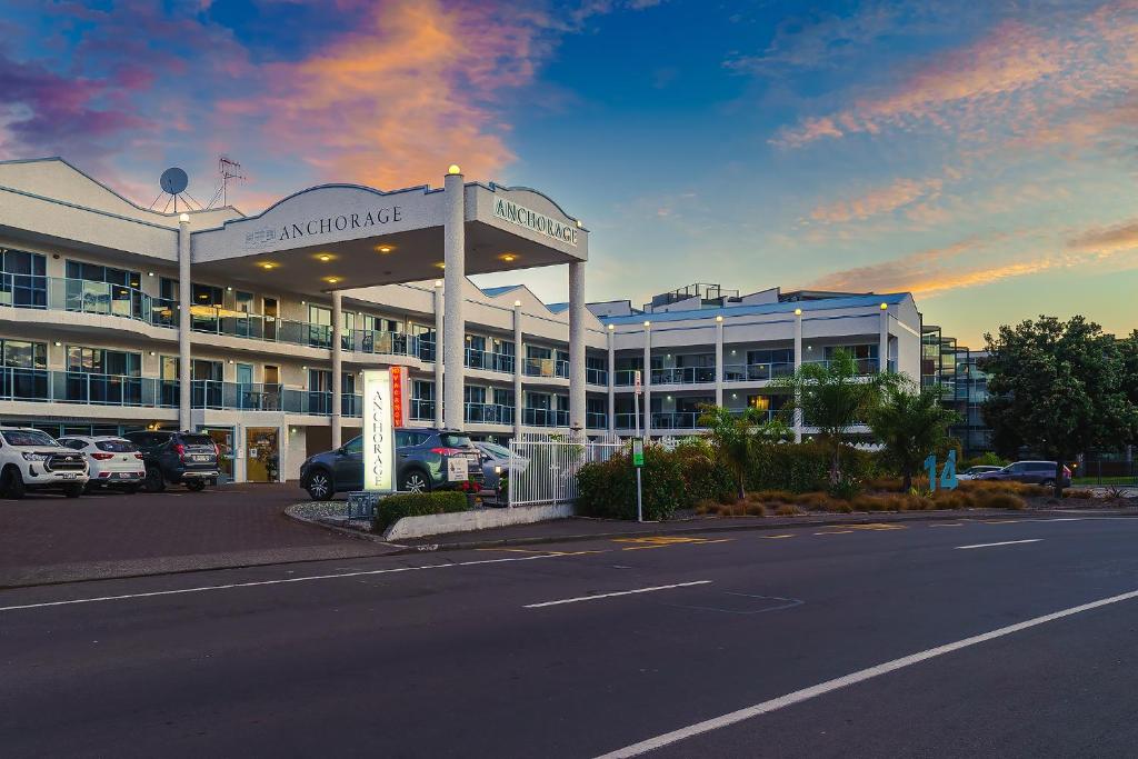 un grand bâtiment avec des voitures garées dans un parking dans l'établissement Anchorage Motor Lodge, à Napier