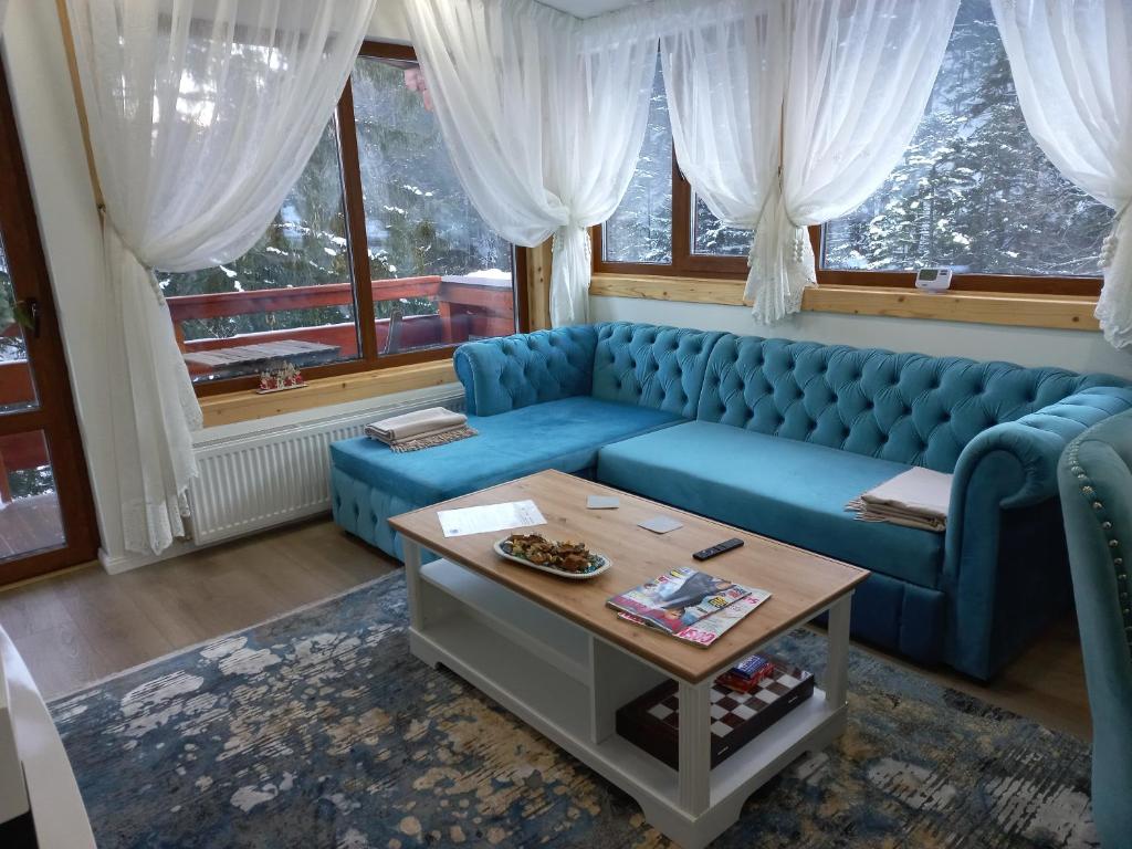 - un salon avec un canapé bleu et une table dans l'établissement Kalinderu luxury ski loft, à Buşteni