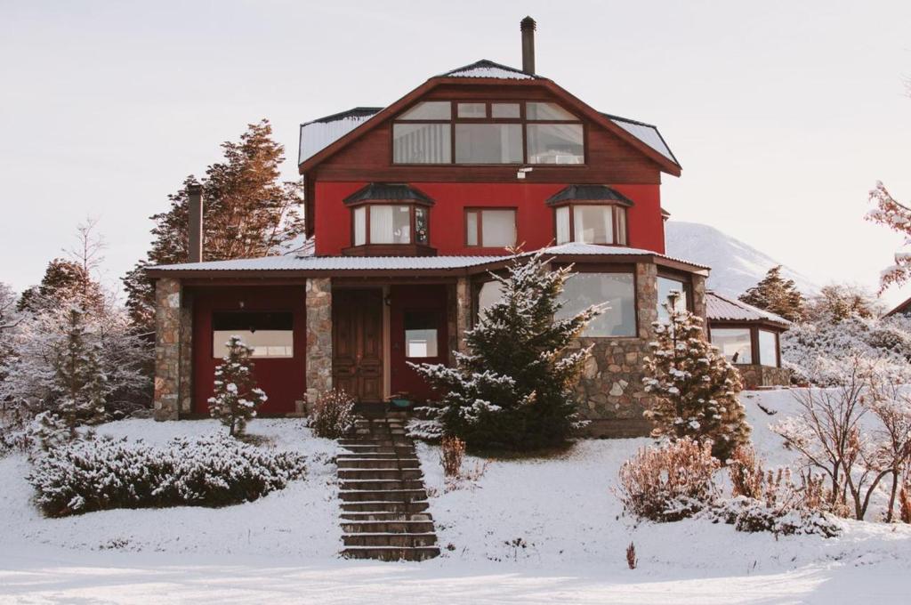 una casa roja con nieve delante en Villa de los Ñires en Ushuaia