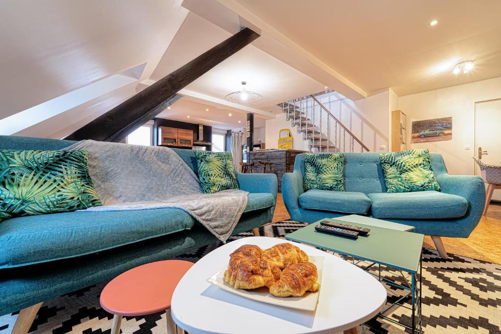 una sala de estar con muebles azules y una mesa con un plato de pan. en Sous les Etoiles Metz Luxembourg Un-Séjour-à-Part en Clouange