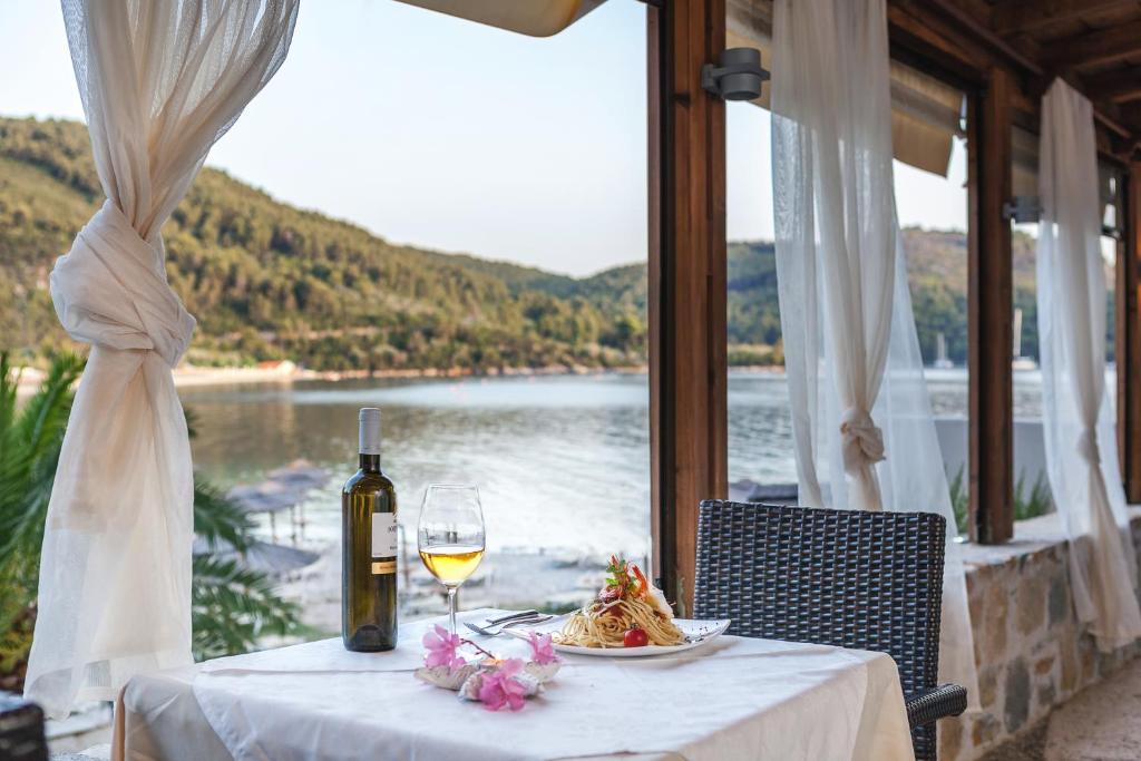 a table with a glass of wine and a plate of food at Blue Green Bay in Panormos Skopelos