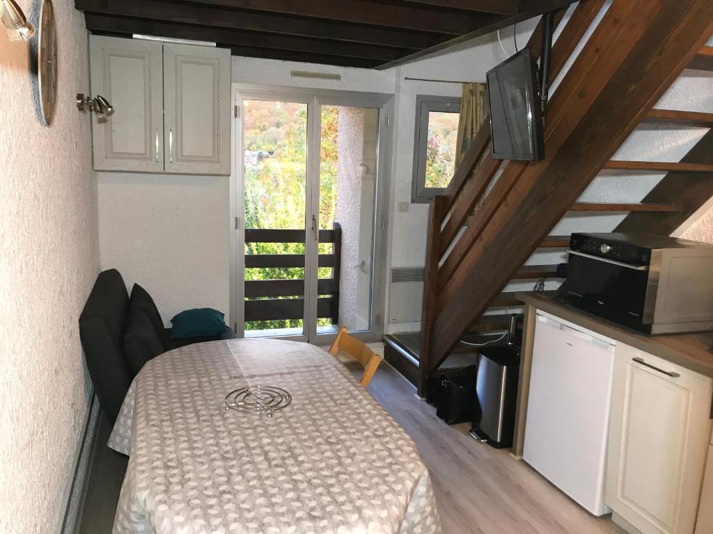 Habitación con mesa y cocina con escaleras. en APPARTEMENT CAUTERETS POUR 4 PERSONNES AVEC PARKING, en Cauterets