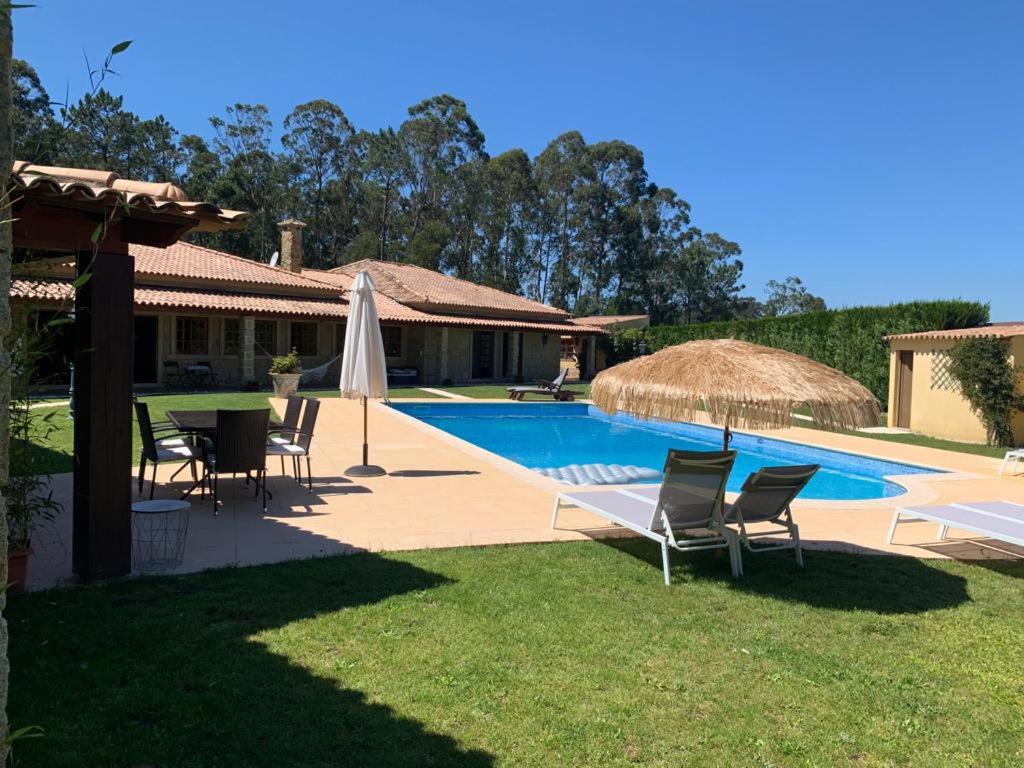 a house with a swimming pool with chairs and a umbrella at VILLA 500 in Barcelos