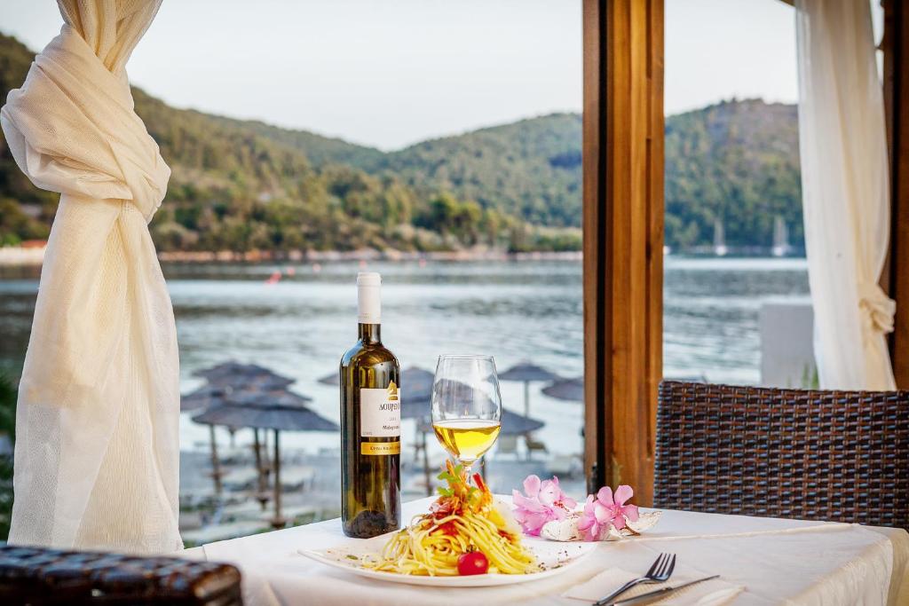 a bottle of wine and a glass on a table with pasta at Blue Green Bay in Panormos Skopelos