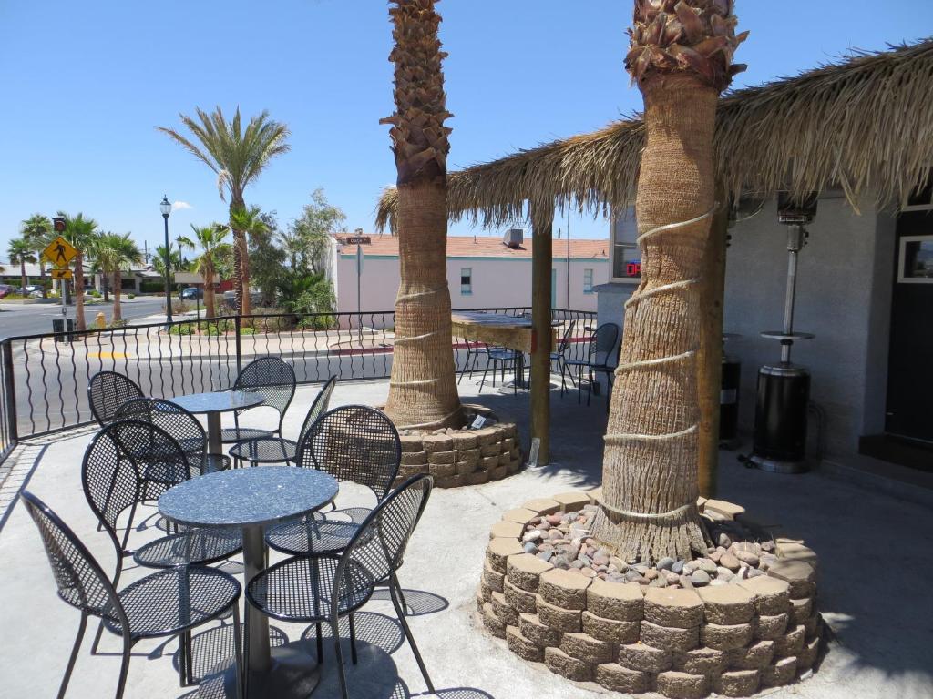a patio with tables and chairs and palm trees at Oasis Boutique Motel in Boulder City
