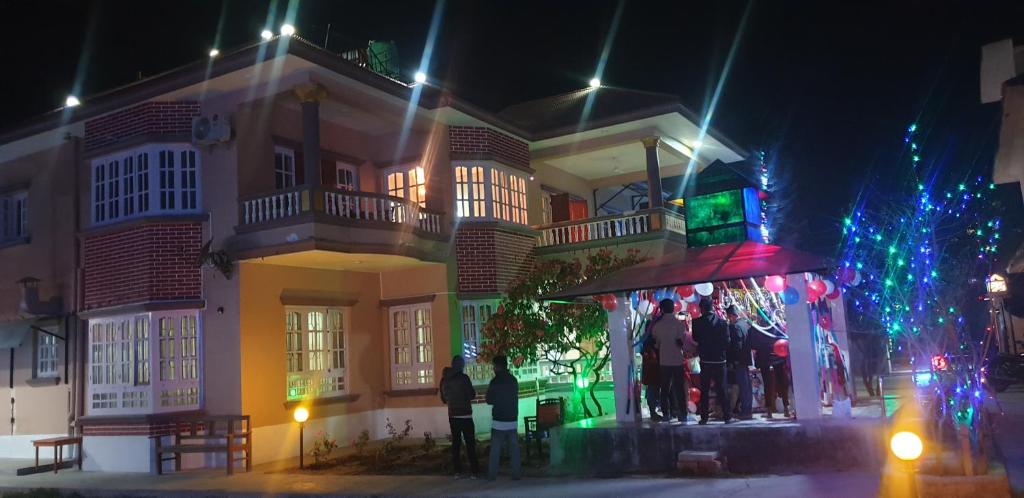 un grupo de personas de pie fuera de un edificio por la noche en London House Resort en Birātnagar