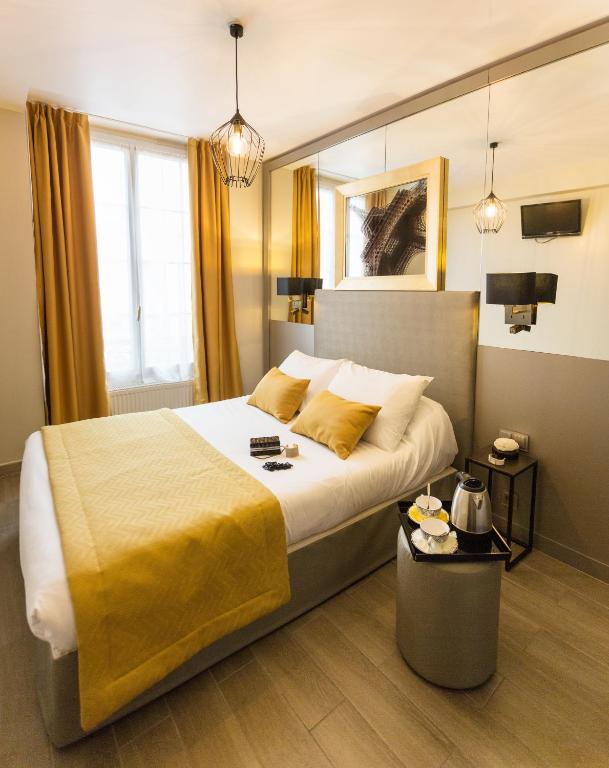 une chambre avec un grand lit avec une couverture jaune dans l'établissement Pratic Hotel, à Paris