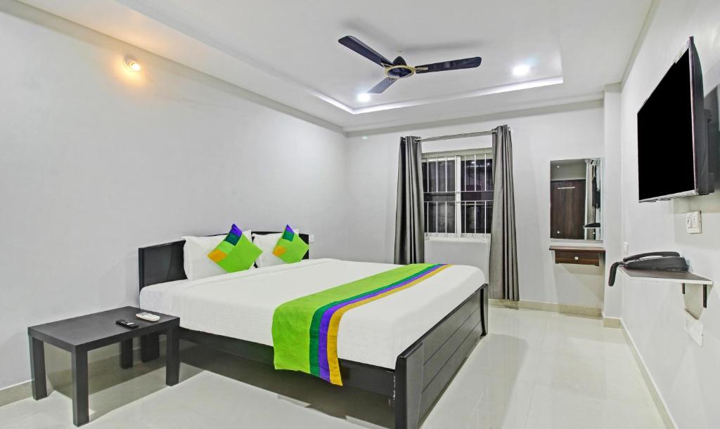 a white bedroom with a bed and a tv at Itsy By Treebo - Sunrise Grand in Hyderabad