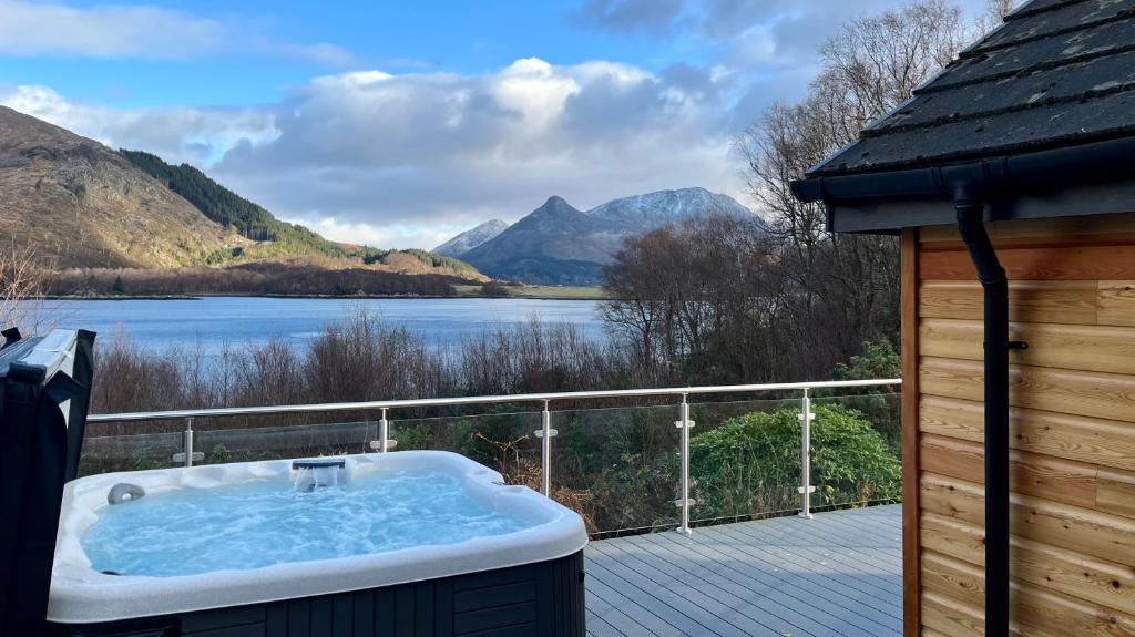 un bain à remous sur une terrasse avec vue sur le lac dans l'établissement The Heronry Hideaway with luxury hot tub, à Ballachulish