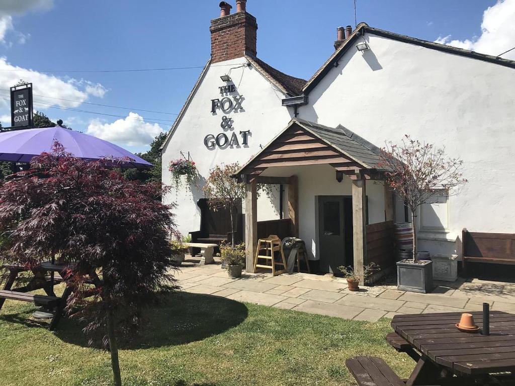 a white building with a roof and a sign on it at Fox and Goat in Waterstock