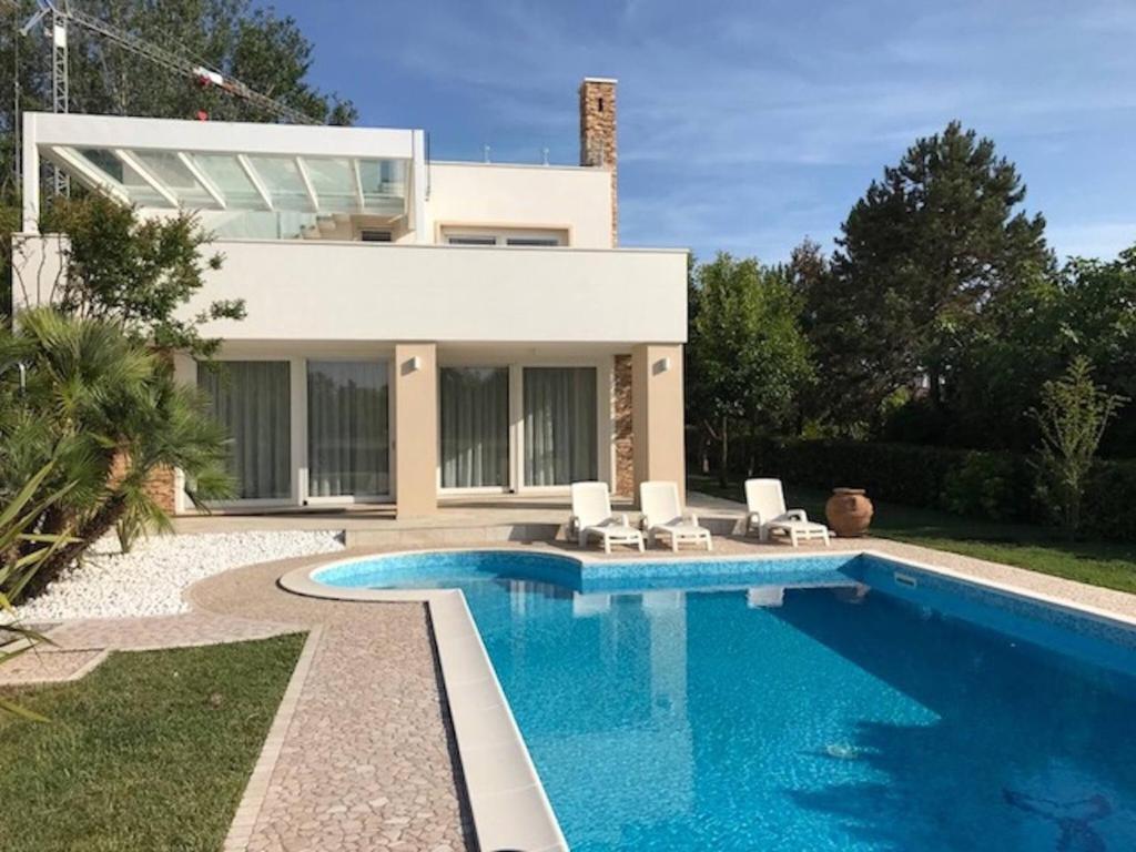 uma villa com piscina em frente a uma casa em Beautiful Modern Villa In Isola Albarella em Ilha Albarella