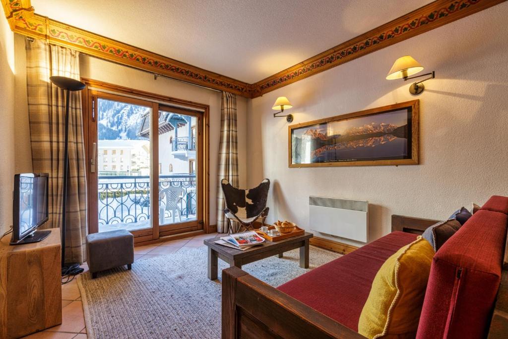 a living room with a couch and a tv and a window at Résidence Le Cristal - Grands Montets 7 - Happy Rentals in Chamonix