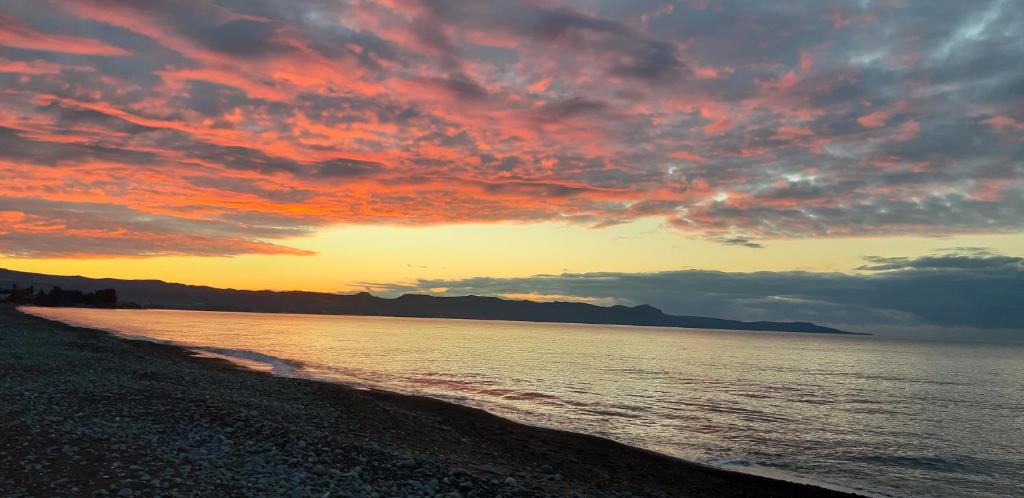Una puesta de sol en la playa con un cielo nublado en SEA CAVES suite, en Peyia