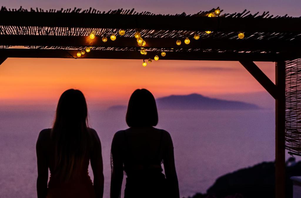 Zwei Frauen stehen auf einem Berg und beobachten den Sonnenuntergang. in der Unterkunft Hotel Il Girasole in Anacapri