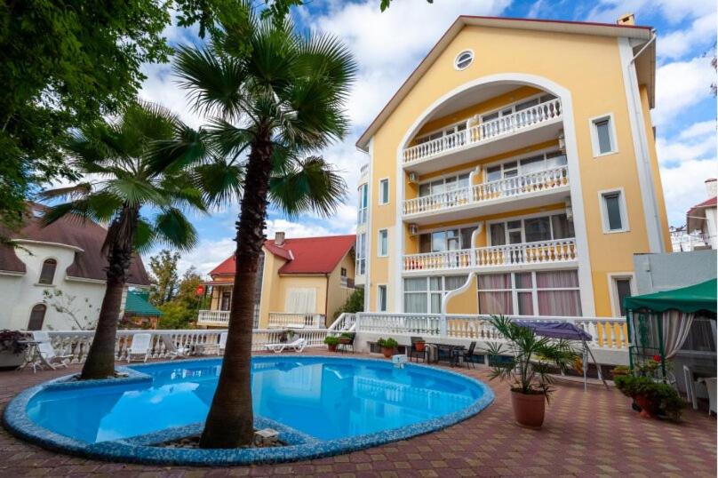 una piscina frente a un edificio con palmeras en Medovaya Hotel, en Adler