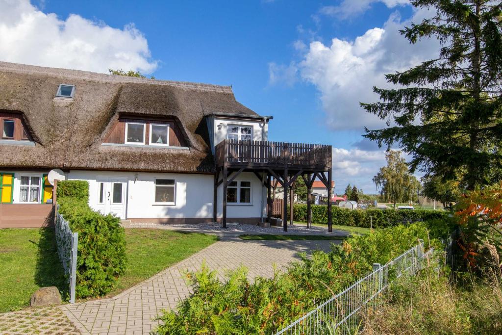 a cottage with a thatched roof and a walkway at Ferienwohnungen Zum Fischerhafen in Freest