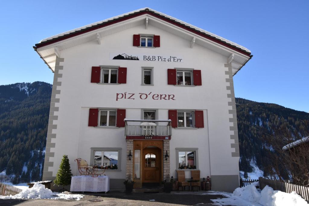 un grand bâtiment blanc avec le nom de pitzo ocar dans l'établissement B&B Piz d'Err, à Tinzen