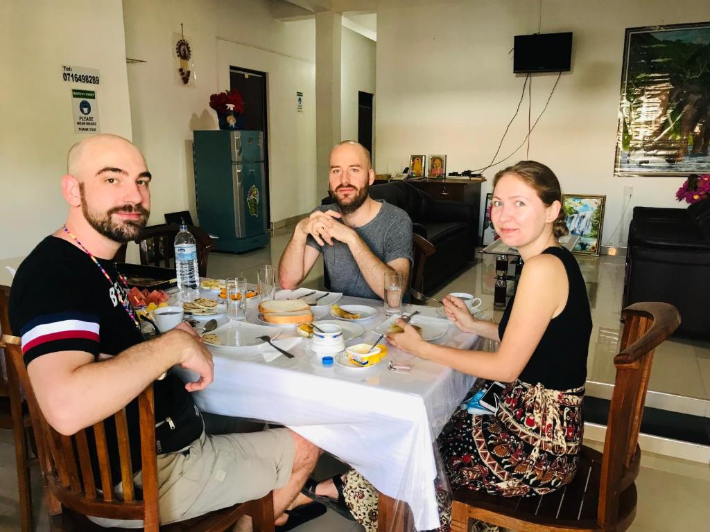 Eine Gruppe von Menschen, die an einem Tisch sitzen und Essen essen. in der Unterkunft Dambulla Tourist Resort in Dambulla