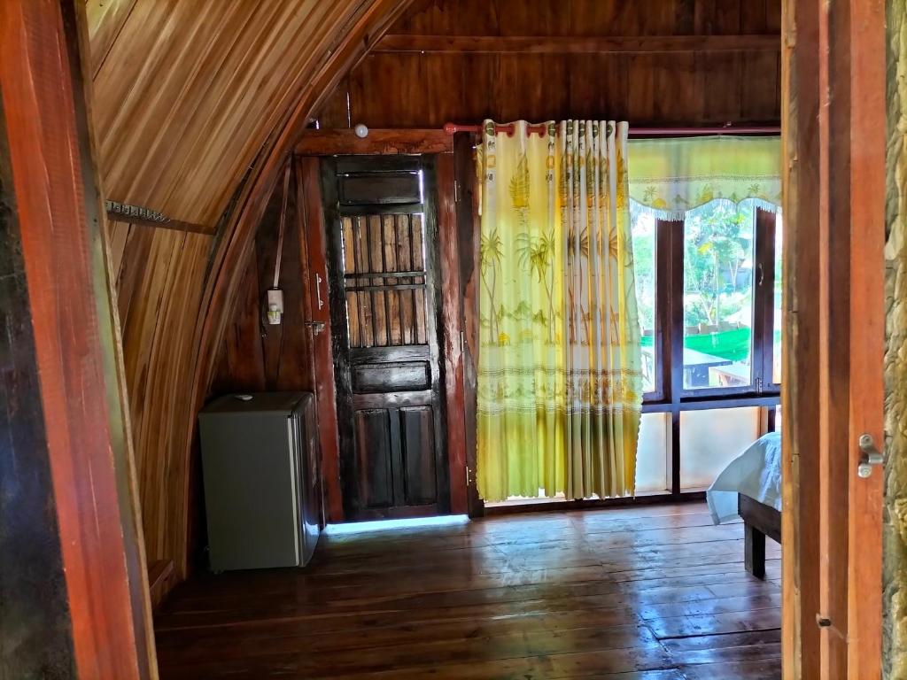 a room with wooden floors and a door and windows at Rice straw Green lodge- resort in Quan Tom