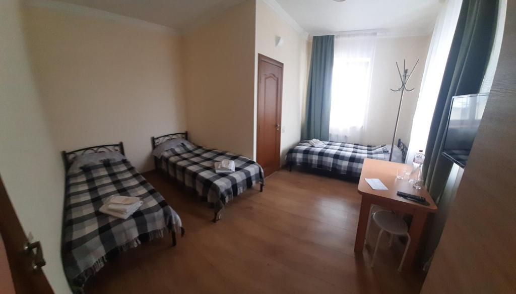 Kleines Zimmer mit 2 Betten und einem Tisch in der Unterkunft Арт-готель "Династія" in Bila Zerkwa