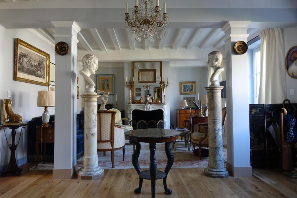 een woonkamer met een tafel en twee witte zuilen bij les chambres de la tour in Le Bec-Hellouin