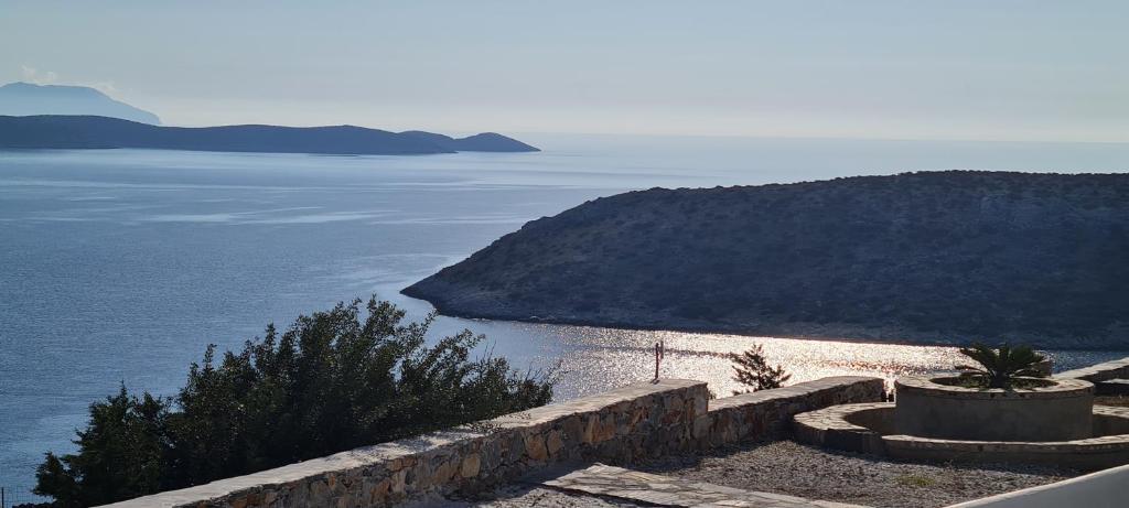 uma vista para um corpo de água com uma parede de pedra em Villa Panorama em Irakleia