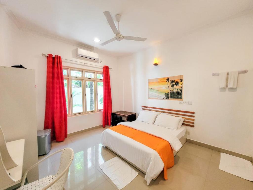 1 dormitorio con 1 cama con cortinas rojas en Alesara Guest House, en Thoddoo