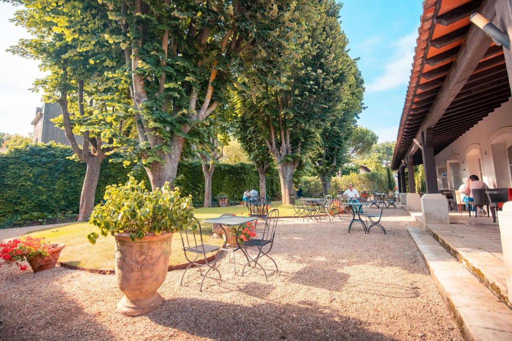 einen Park mit Tischen, Stühlen und Bäumen sowie einem Tisch und Stühlen in der Unterkunft Hôtel Le Donjon - Cœur de La Cité Médiévale in Carcassonne