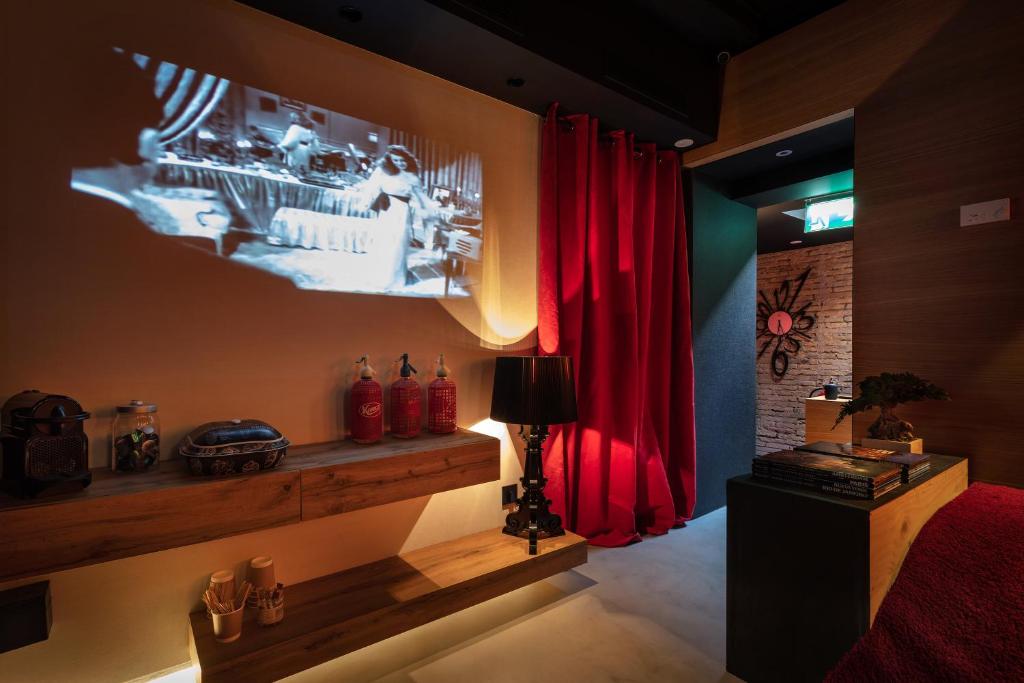 a bedroom with red curtains and a tv on the wall at Zrooms&Suites Hostel Boutique in Zaragoza