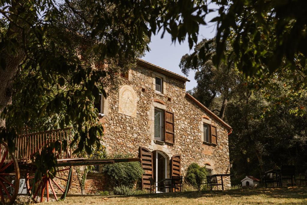 una vieja casa de piedra con un árbol en Paratgea, en Llinars del Vallès