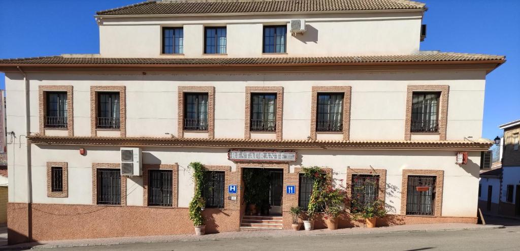 Un grand bâtiment blanc avec des fenêtres donne sur une rue. dans l'établissement Hotel Casa Marchena, à Vilches