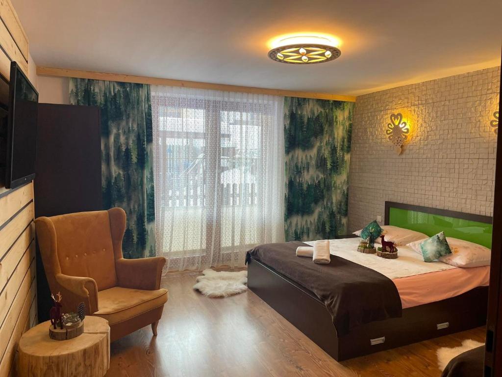 Un dormitorio con una cama y una silla y un televisor. en Willa Omega, en Zakopane