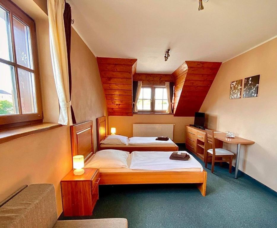 a bedroom with two beds and a table and a desk at Penzión Kingo in Nemšová