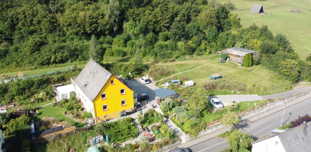 ein gelbes Haus auf einem Hügel neben einer Straße in der Unterkunft Urlaub am Auberg in Gerolstein