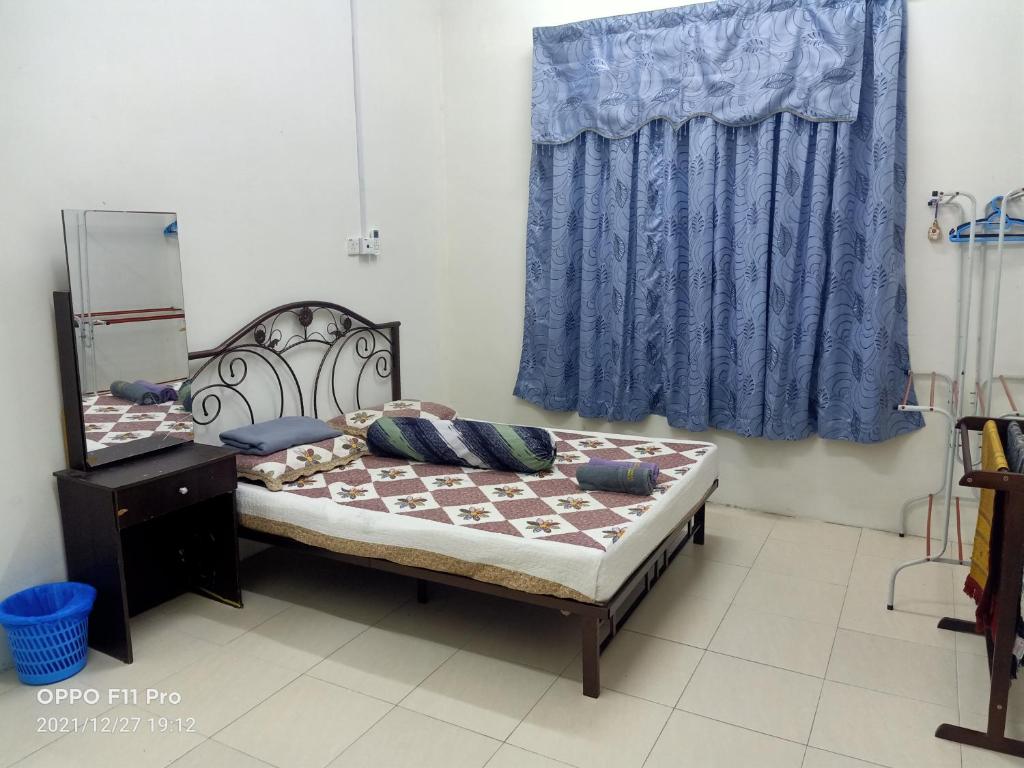 a bedroom with a bed and a blue curtain at YIE HOMESTAY muslim friendly in Kampong Bukit Dukong