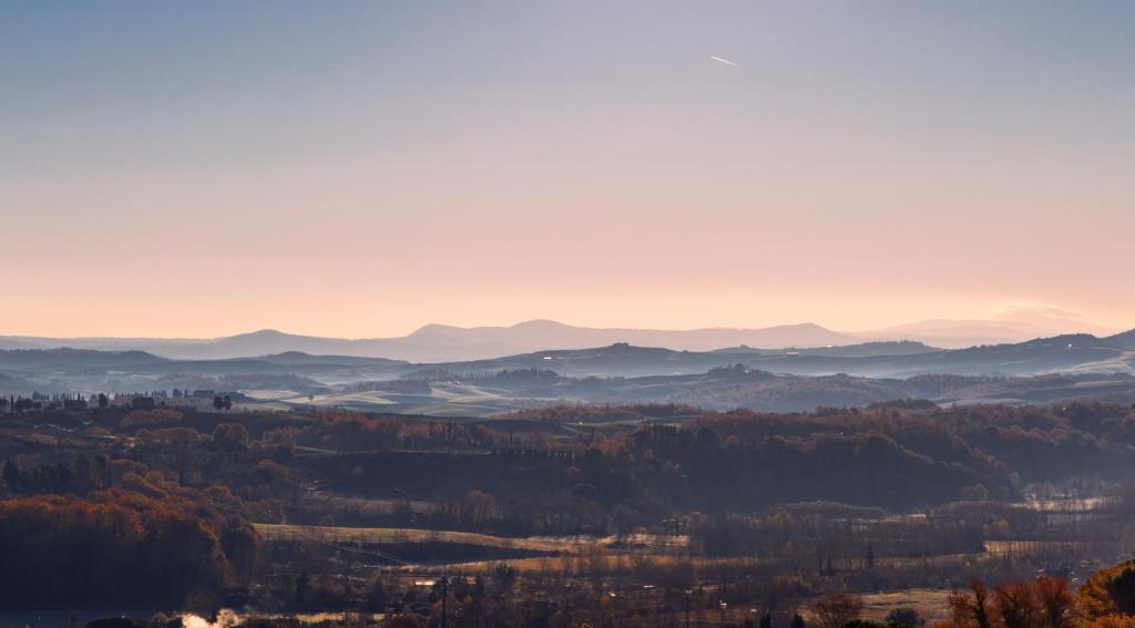 a view of a valley with trees and mountains at Borgo Argiano in Castelnuovo Berardenga