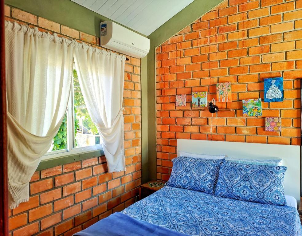 フロリアノポリスにあるSuíte Rústicaのレンガ壁のベッドルーム(ベッド1台、窓付)