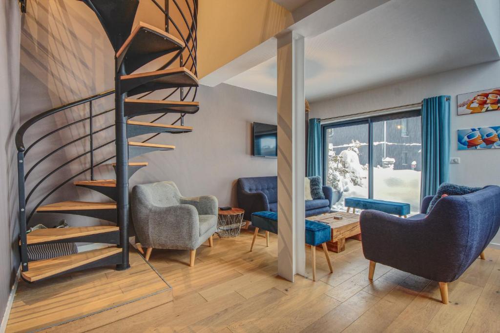 a living room with a spiral staircase and chairs at Maison Des Praz Chamonix in Chamonix